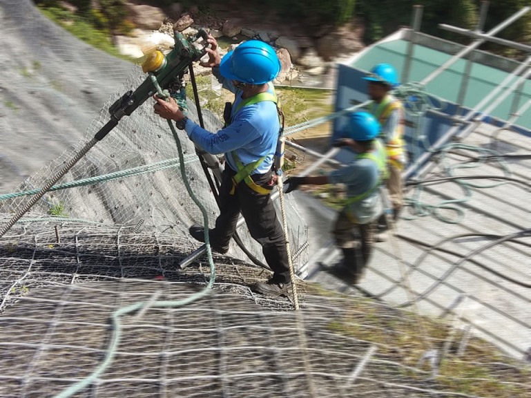 MEGA Philippines worker drilling into a reinforced slope for renewable energy infrastructure protection