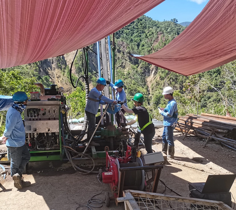MEGA Philippines crew working with a drilling rig and geophysical logging equipment at a mountain project site
